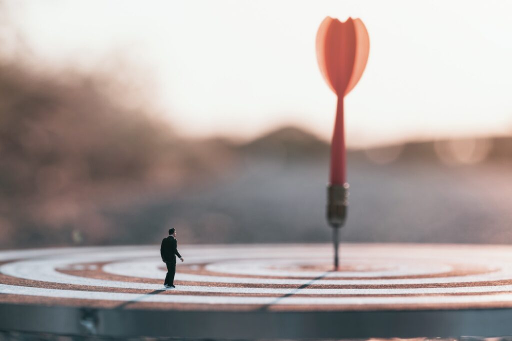 Businessman standing lookup blurred or out of focus red dart arrow hitting target centre dartboard