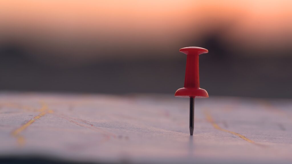 Close up red pin push map under sunset background. business focus and target concept.