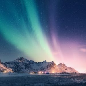 Green and purple aurora borealis over snowy mountains